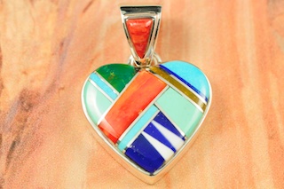 Genuine Turquoise, Spiny Oyster Shell, Sugilite and Blue Lapis inlaid between ribbons of Sterling Silver. Stunning Heart Pendant with precision inlay on the bale and pendant. Free 18" Sterling Silver Chain with purchase of pendant. Designed by Navajo Artist Calvin Begay. Signed. 